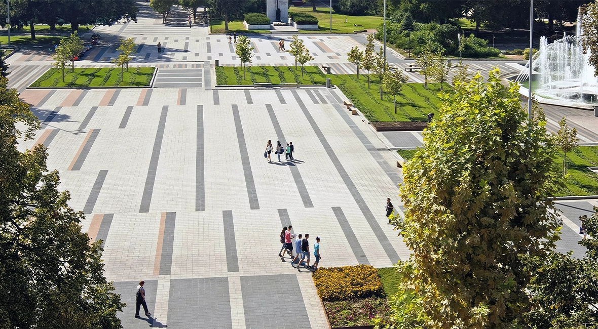 Öffentlicher Platz mit viel Grün und einem Brunnen auf der rechten Seite (Foto)