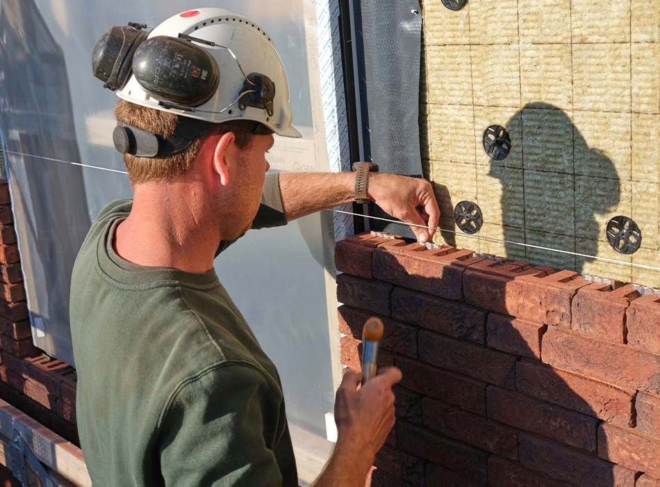 Mann verlegt Ziegel bei der Renovierung und Erweiterung der historischen Orangerie in Baarn, Niederlande mit dem Wienerberger ClickBrick-System (Foto)